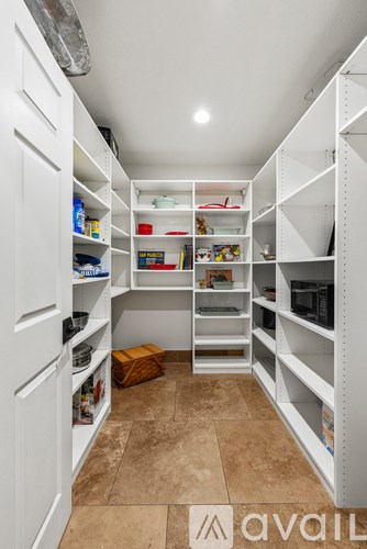 A white pantry with shelves and containers on the floor.