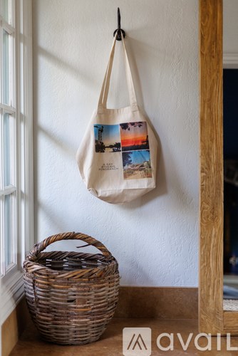 A tote bag with a picture of a beach scene on it is hanging on a wall.