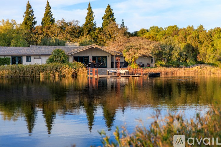 A house is situated on the water with trees in the background.