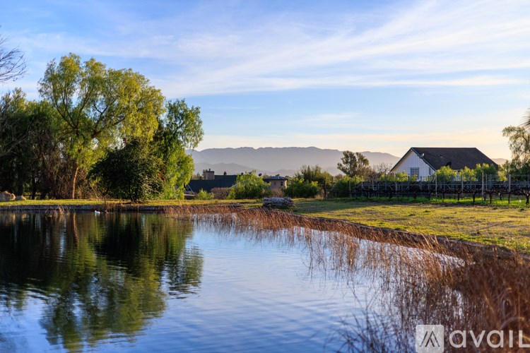 A serene landscape with a house, trees, and a reflective body of water.