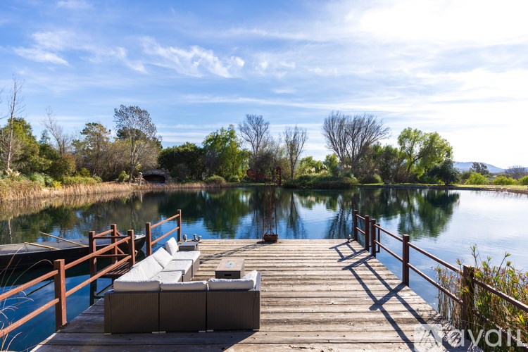 A wooden dock with white cushioned seating over a calm body of water.