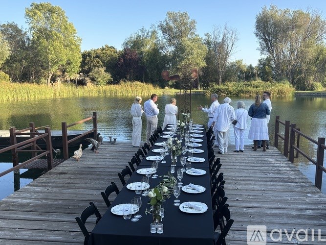 A group of people are standing on a dock by a lake.
