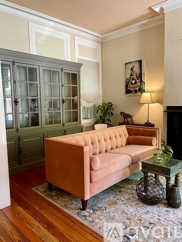 A living room with a pink couch and a glass table.