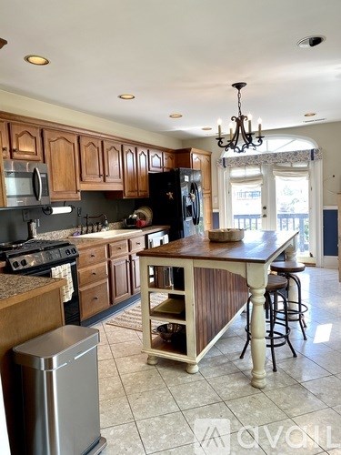 A kitchen with a large island and a stainless steel refrigerator.
