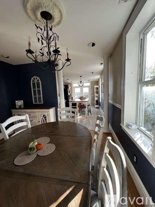 A dining room with a brown table and white chairs.