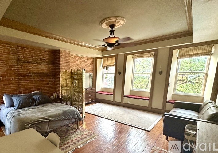 A bedroom with a brick wall and a ceiling fan.