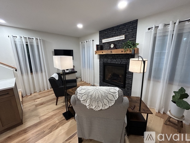 A cozy living room with a fireplace and a chair with a white shawl draped over it.