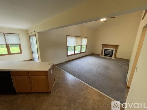 A spacious room with a kitchen area and a fireplace.