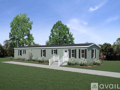 A house with a greenish exterior and a white door is surrounded by greenery.
