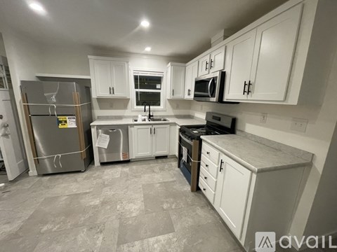 A kitchen with white cabinets and a grey floor.