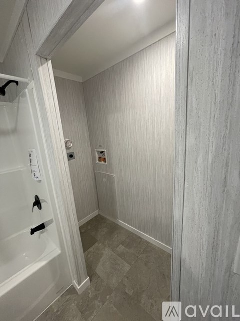 A bathroom with a white tub and grey tiles.