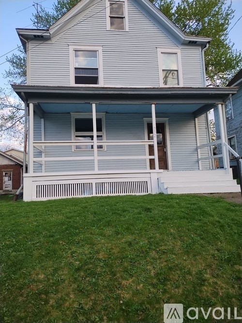 A two-story house with a porch and a white picket fence.
