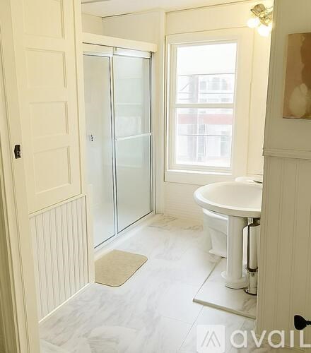 A white bathroom with a glass shower door and a white sink.