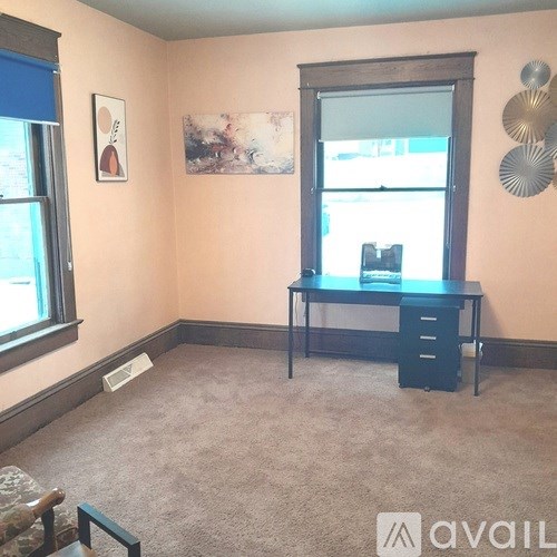 A room with a desk and chair in front of a window.