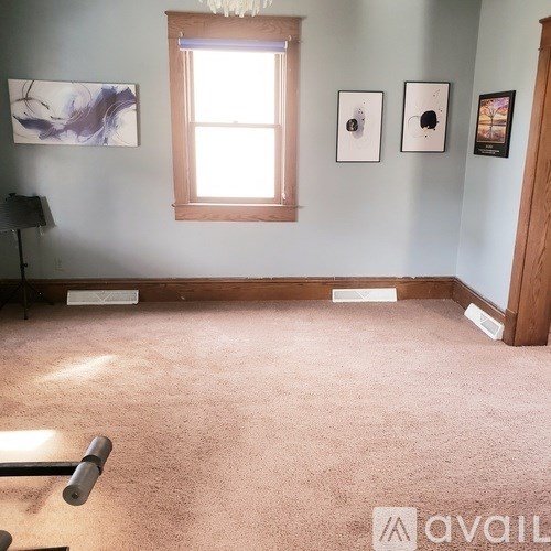 A room with a window, a lamp, and pictures on the wall.