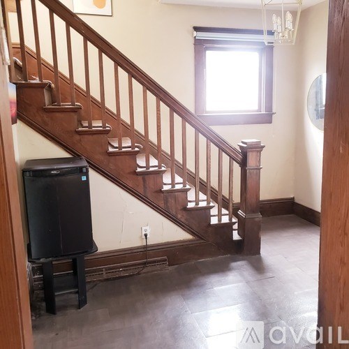 A staircase with a wooden banister and a window above it.