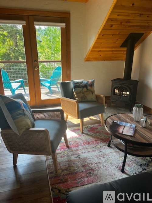 A living room with a wood stove and a table with a vase on it.