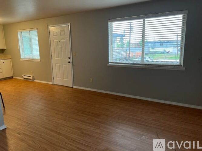 A room with wooden flooring and a window with blinds.