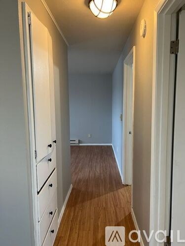 A hallway with a wooden floor and white walls.