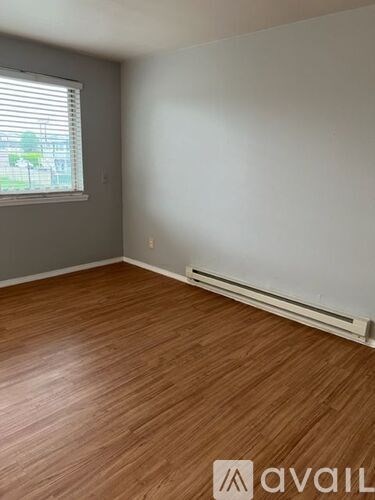 A room with wooden flooring and a window with blinds.