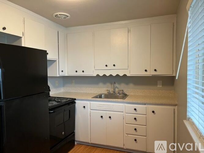 A kitchen with white cabinets and a black refrigerator.