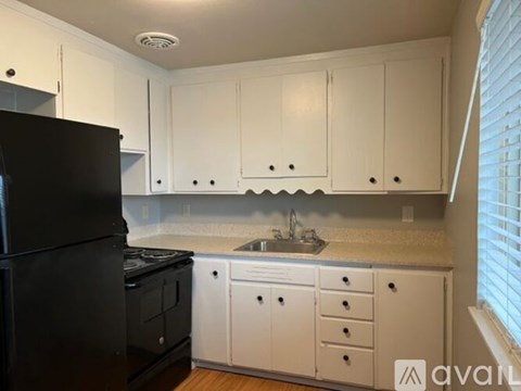 A kitchen with white cabinets and a black refrigerator.