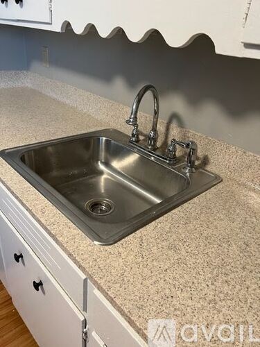 A kitchen sink with a granite countertop and white cabinets.