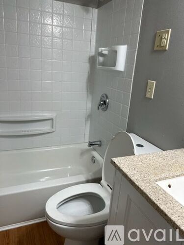 A white toilet in a bathroom with a white tiled wall.
