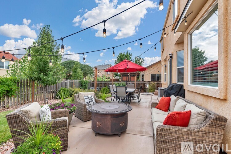 A patio with a table, chairs, and a red umbrella.