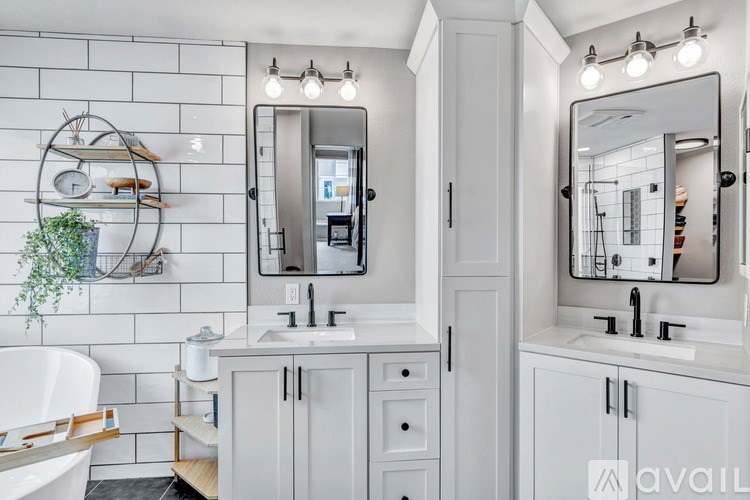 A bathroom with a white tub, sink, and mirror.