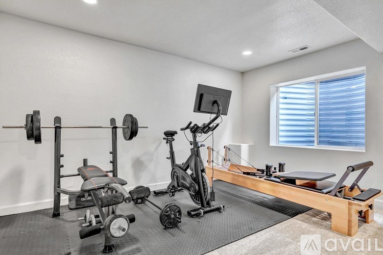 A home gym with a variety of equipment including a rowing machine, dumbbells, and a bench.