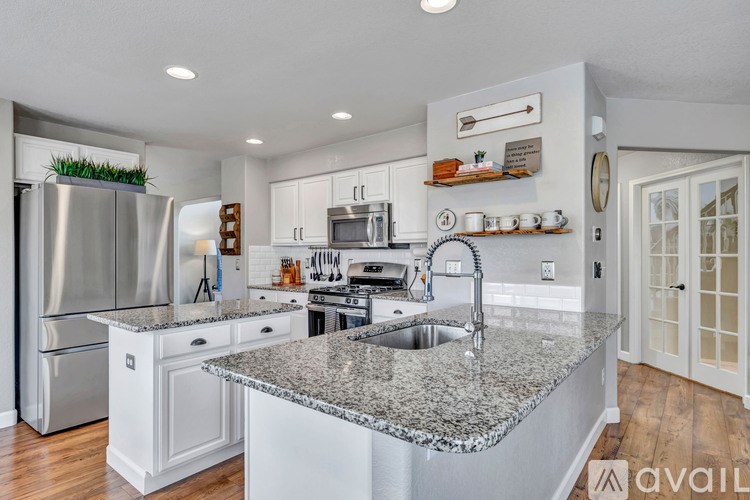 A modern kitchen with granite countertops and stainless steel appliances.