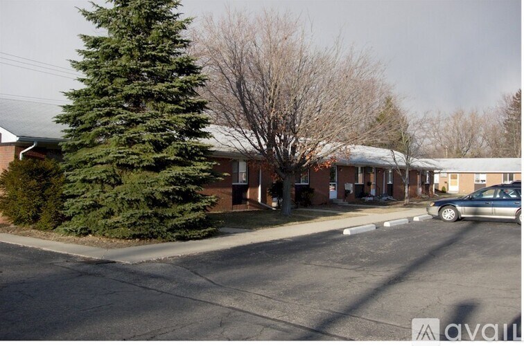 A parking lot in front of a building with a silver car parked.