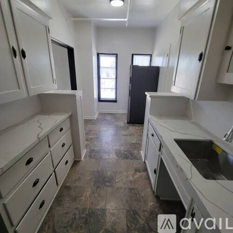 A kitchen with white cabinets and a black refrigerator.