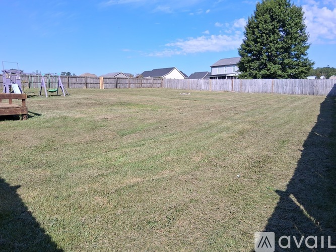 A grassy field with a wooden structure and a fence in the background.