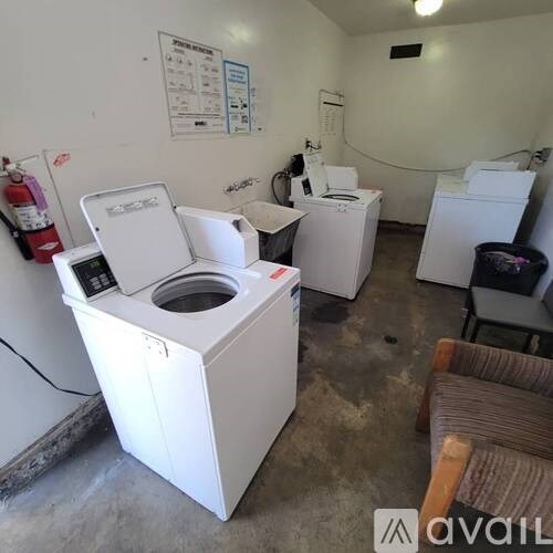 A white washing machine is in the foreground of a laundry room.