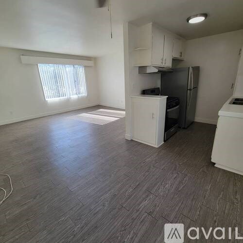 A kitchen area with a refrigerator, stove, and cabinets.