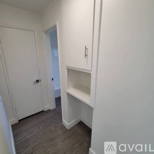A white door is on the left and a white cabinet with a shelf is on the right.