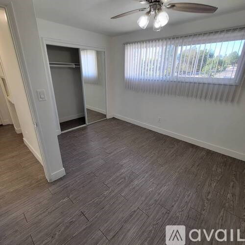 A room with a ceiling fan and a window with blinds.