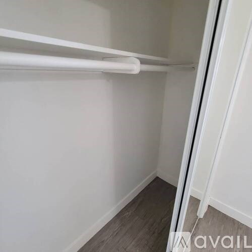 A white closet with a white shelf and a white door.