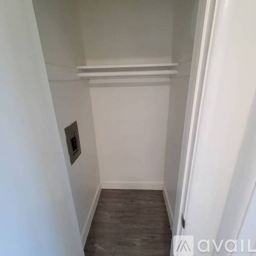 A small white room with a grey floor and a white door.