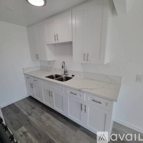 A kitchen with white cabinets and a marble countertop.