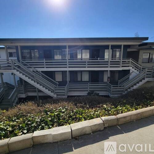 A building with a balcony and stairs in front of it.