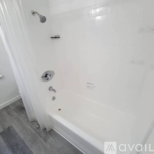 A white bathtub with a shower head and a curtain.