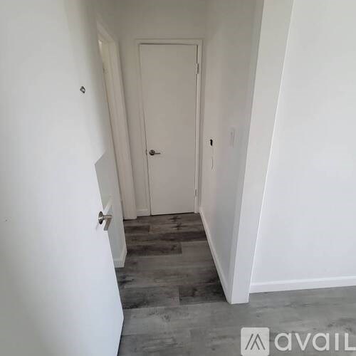 A hallway with a door and a wall on the left.