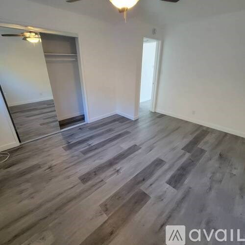 A room with wooden flooring and a staircase in the background.