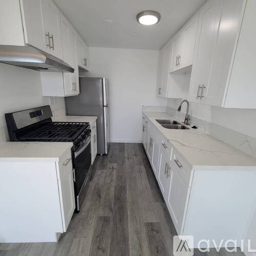 A kitchen with white cabinets and a grey floor.