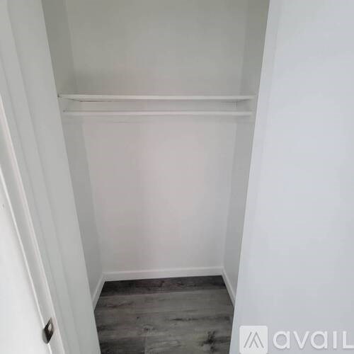 A white closet with a shelf and a door.