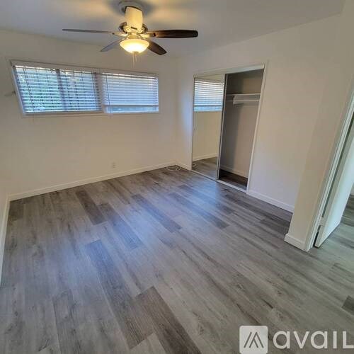 A room with a ceiling fan and wooden flooring.