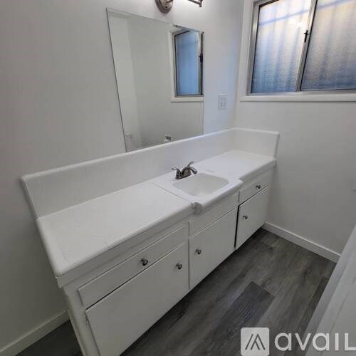 A white bathroom vanity with a sink and mirror.